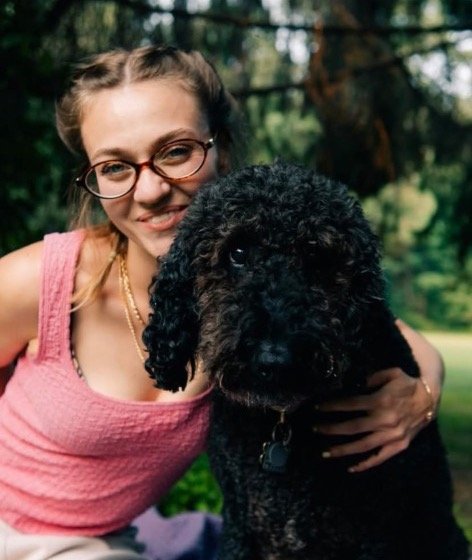 Anna C. enjoying outdoor enrichment time with a happy black doodle